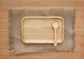 Wooden tray and spoon on sack against wood board background.