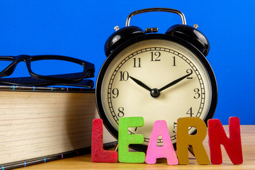 Education concept with books, alarm clock,glass with word LEARN.