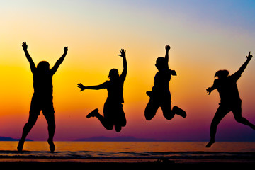 A group of women rise hands up to sky freedom concept with blue sky and beach sunset.
