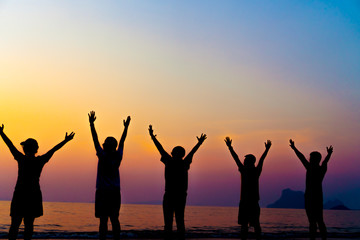 Fototapeta na wymiar A group of women rise hands up to sky freedom concept with blue sky and beach sunset.