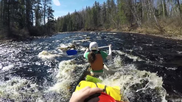 Wide point of view canoeing whitewater wilderness rapids on river with woman paddler getting soaked Slow Motion