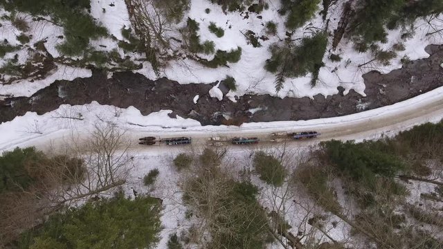 Top down drone shot of three horse teams riding a narrow mountain valley next to a stream