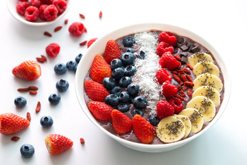 Acai Berry superfoods smoothies white bowl with chia seeds, strawberry, goji berry, coconut, blueberry, raspberry toppings, and chocolate chip on white background