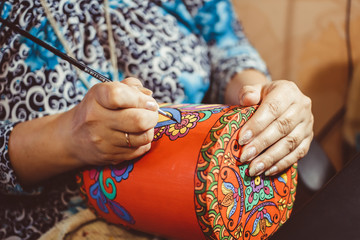 man draws with a brush on wood