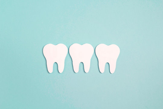 White paper teeth on blue background. Dental health concept. Flat lay, top view, copy space for text.