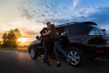 Couple standing near the car in a summer evening