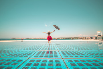 Happy woman traveler dances on outdoor disco floor in Zadar, Croatia. - obrazy, fototapety, plakaty