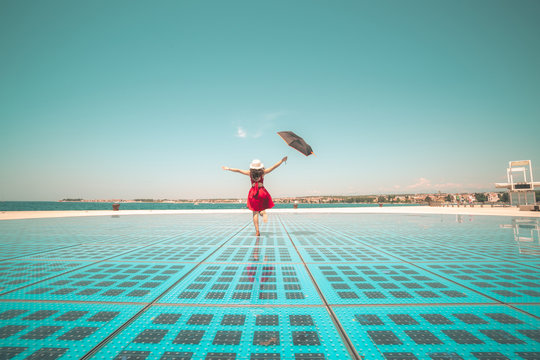 Happy woman traveler dances on outdoor disco floor in Zadar, Croatia.