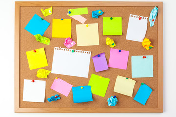 Cork board with several colorful blank notes with pins
