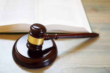 Judges gavel or law mallet on sound block and open law book on wooden table. Legal law, education, judgement  concept.