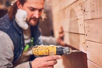 Male carpenter working on old wood in a retro vintage workshop.