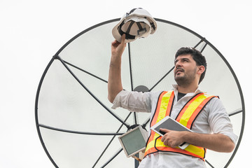 Professional technician or engineer standing on roof top of building working with satellite dish....