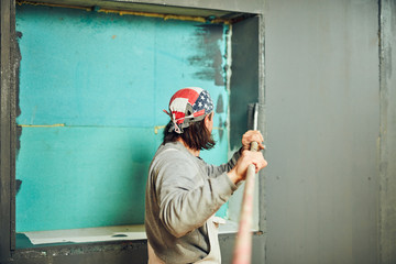Painter painting walls with a extender roller indoors.