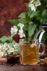 Green tea with jasmine in cup and teapot on wooden table.