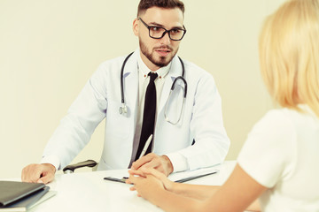 Male doctor is talking to female patient in hospital office. Healthcare and medical service.