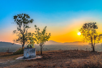 Naklejka premium scenery sunset behind the bell and golden Buddha statue on hilltop of Baan Ngao temple Rarong province Thailand. .