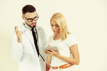 Male doctor and female patient looks at tablet computer for health data record. Healthcare and...