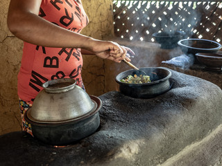 Young woman cooking rice and curry in traditional rural kitchen. Eco village Hiriwadunna, Sri Lanka, March 10, 2019.