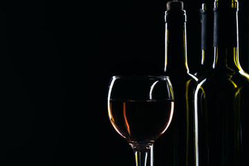  wine bottle and wine glass in a black background