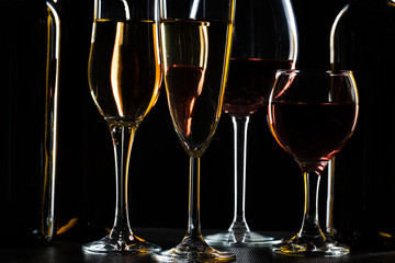 Bottles of wine and different glasses of wine on a dark background