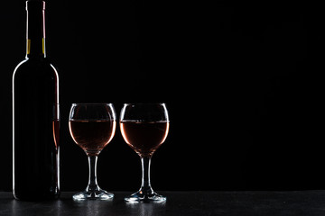Bottles of wine and different glasses of wine on a dark background