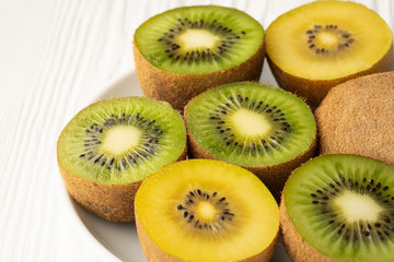 Close up slices of green and yellow golden kiwi in a white plate on the table