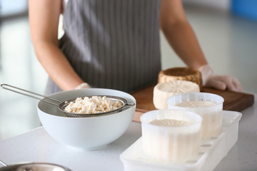 Woman preparing tasty cheese in kitchen