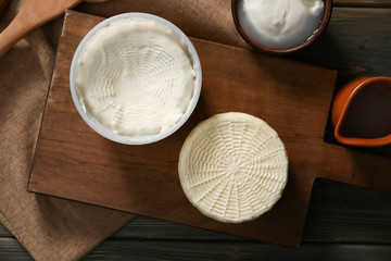 Wooden board with tasty cheese on table