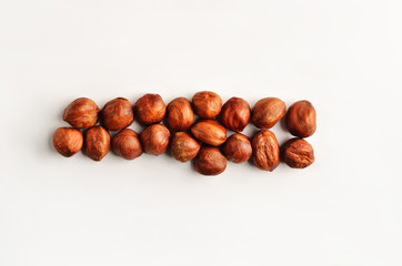 A horizontal row of dry raw hazelnuts on a studio white background.
