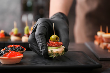 Chef preparing tasty canapes for serving, closeup