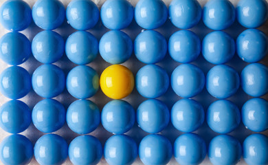Yellow ball among blue ones, top view. Concept of uniqueness