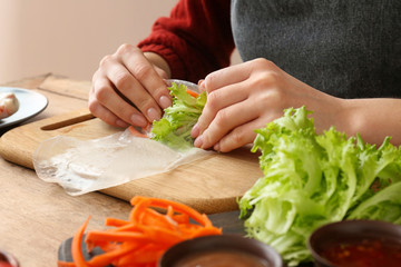 Woman preparing tasty spring rolls, closeup