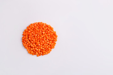 A handful of raw orange lentils grains on a studio white background.