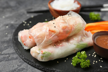 Tasty spring rolls on slate plate, closeup