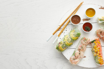 Tasty spring rolls with sauces on white table