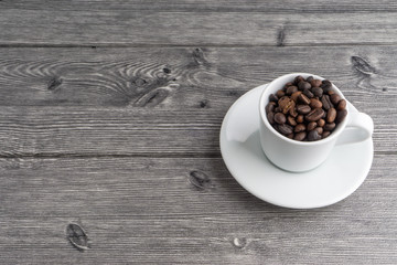 Coffee cup and coffee beans on wooden background. Top view and selective focus