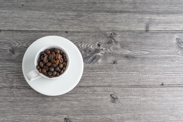 Coffee cup and coffee beans on wooden background. Top view and selective focus