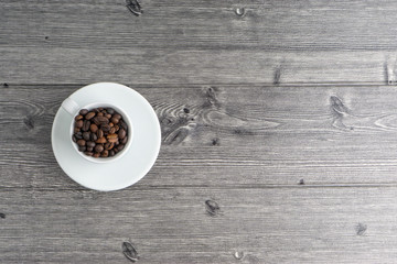 Coffee cup and coffee beans on wooden background. Top view and selective focus