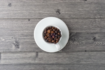 Coffee cup and coffee beans on wooden background. Top view and selective focus