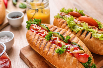 Board with tasty hot dogs on table, closeup