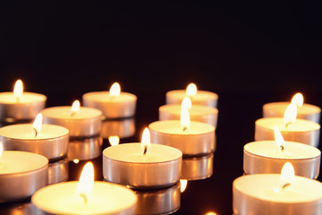 Many burning candles as symbol of mourning on dark background