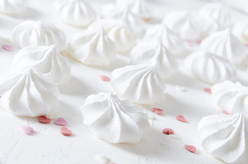 Closeup of tasty meringues and decorations in shape of hearts on white table
