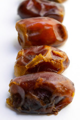 Sweet dry dates laid out in a row, isolated on white background.