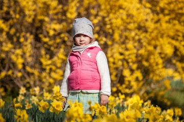 cute girlon a background field with yellow flowers, happy cute and beautiful kid having fun with yellow flowers in spring in park, cheerful holidays outdoors, healthy lifestyle