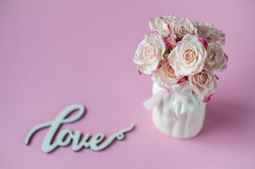 Coral roses on pink background and Love word. Postcard concept. Happy Mother's Day, Women's Day or Birthday. Minimalism, selective focus.