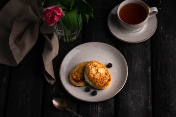 pancakes on a brown backdrop, cup of tea, tulips on background