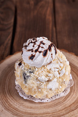 Airy dessert with meringue in chocolate drops with prunes and butter cream in a wooden stand on a wooden background. Close-up