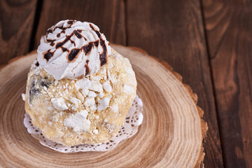 Airy dessert with meringue in chocolate drops with prunes and butter cream in a wooden stand on a wooden background. Close-up