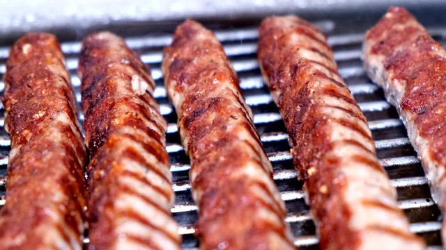 Closeup slowmo of sausage kebabche on a barbecue grill in a kitchen