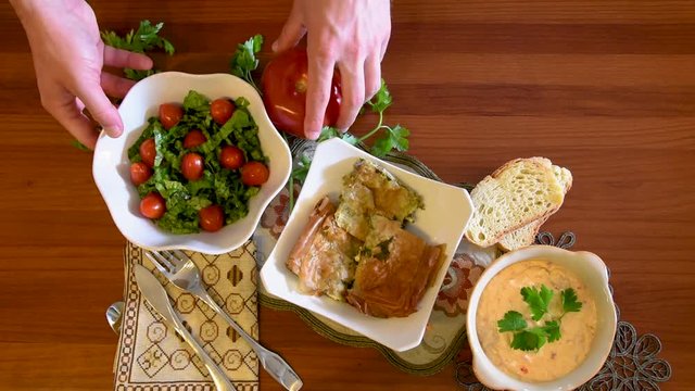 Healthy mediterranean cuisine, three dishes concept for lunch or dinner. Closeup of taking the letuce salad and the tomato from the table in slow motion